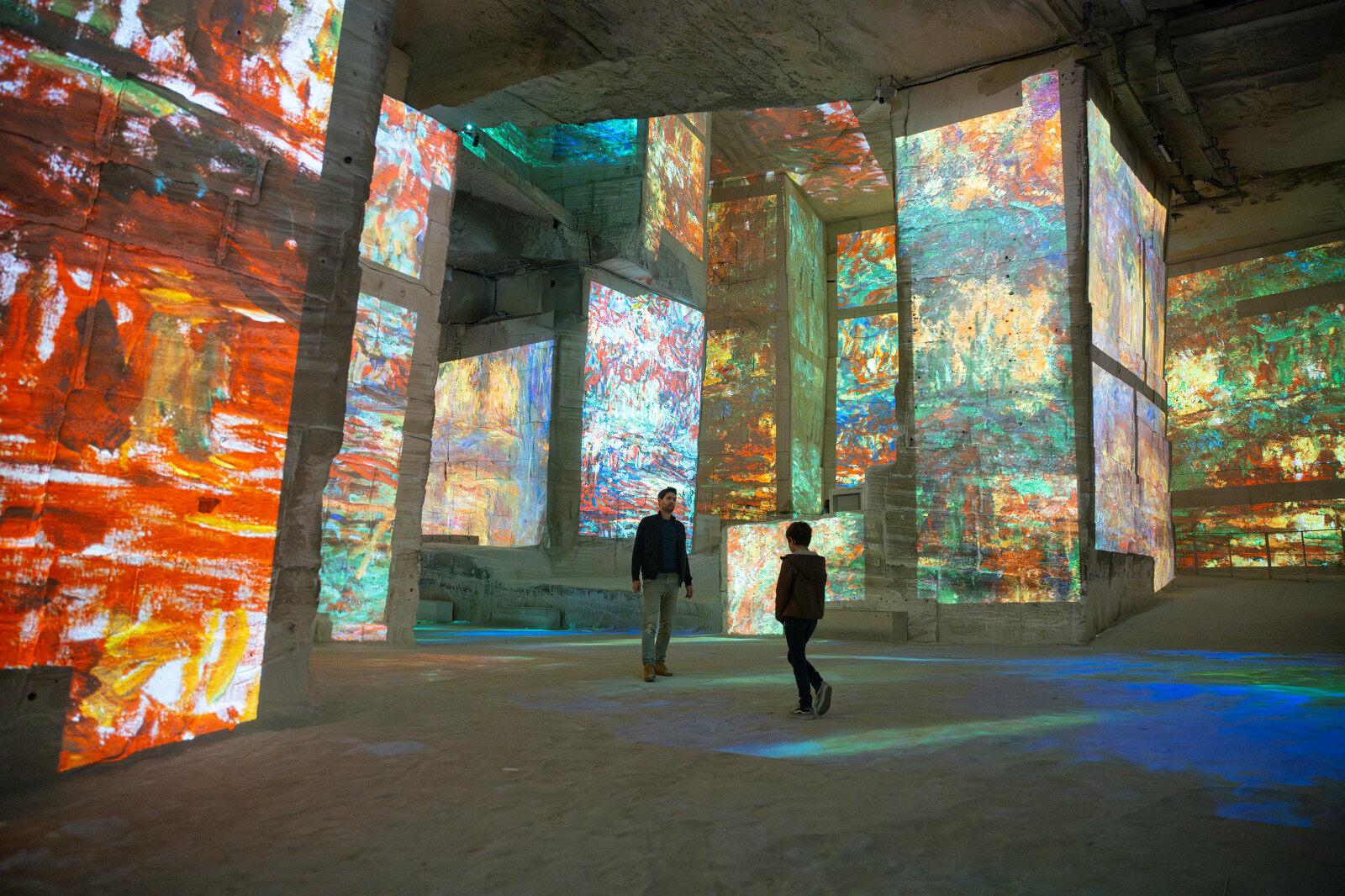 Monet projections at Carrières des Lumières, two people exploring illuminated quarry walls.