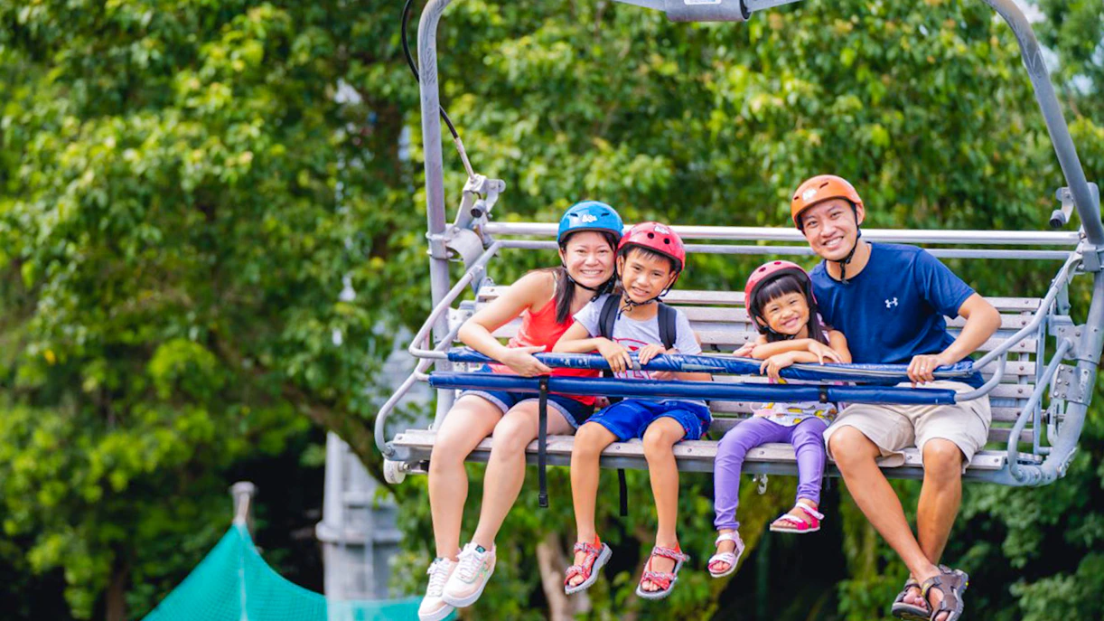 Family enjoying Skyline Luge Singapore ride with lush greenery in the background.