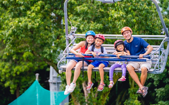 Family enjoying Skyline Luge Singapore ride with lush greenery in the background.