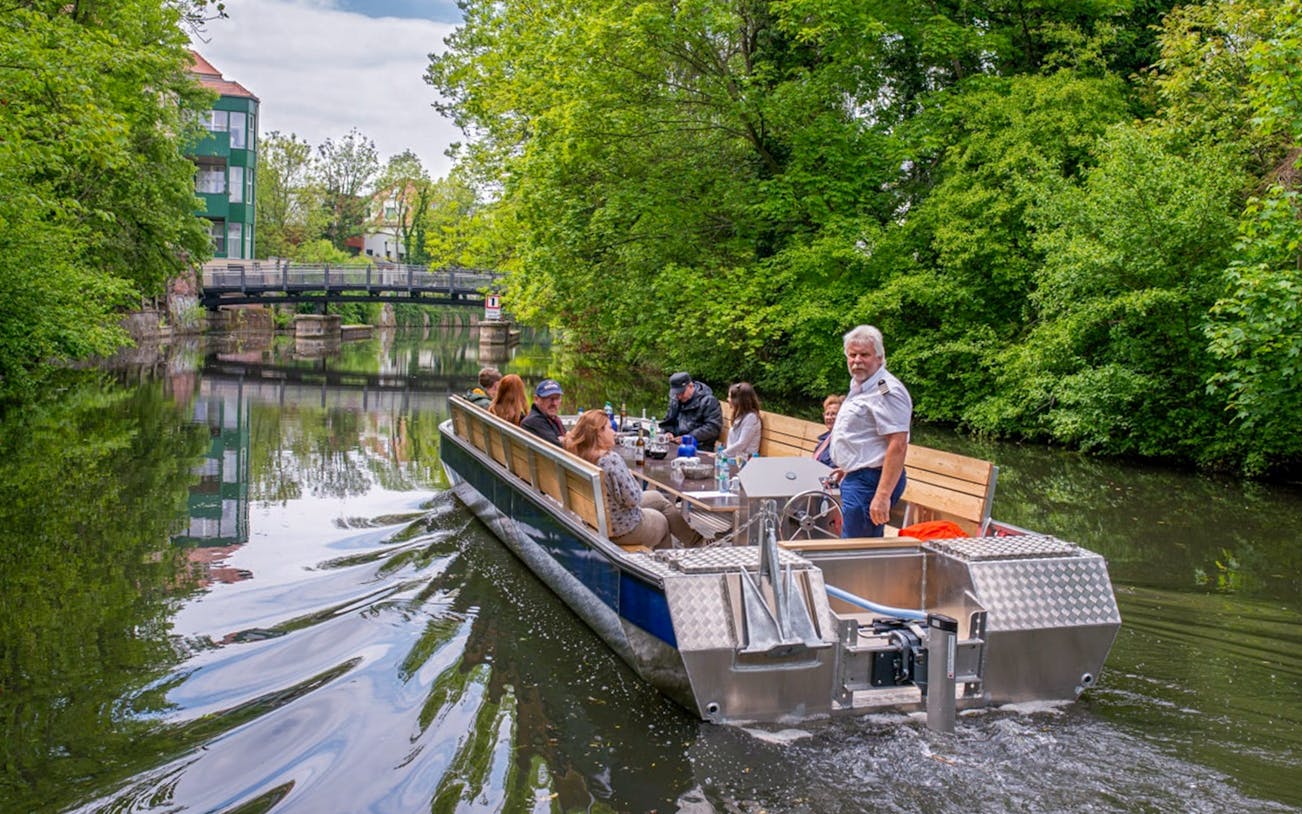 Guests on a motorboat tour of Karl Heine Canal in Leipzig, passing under a bridge.