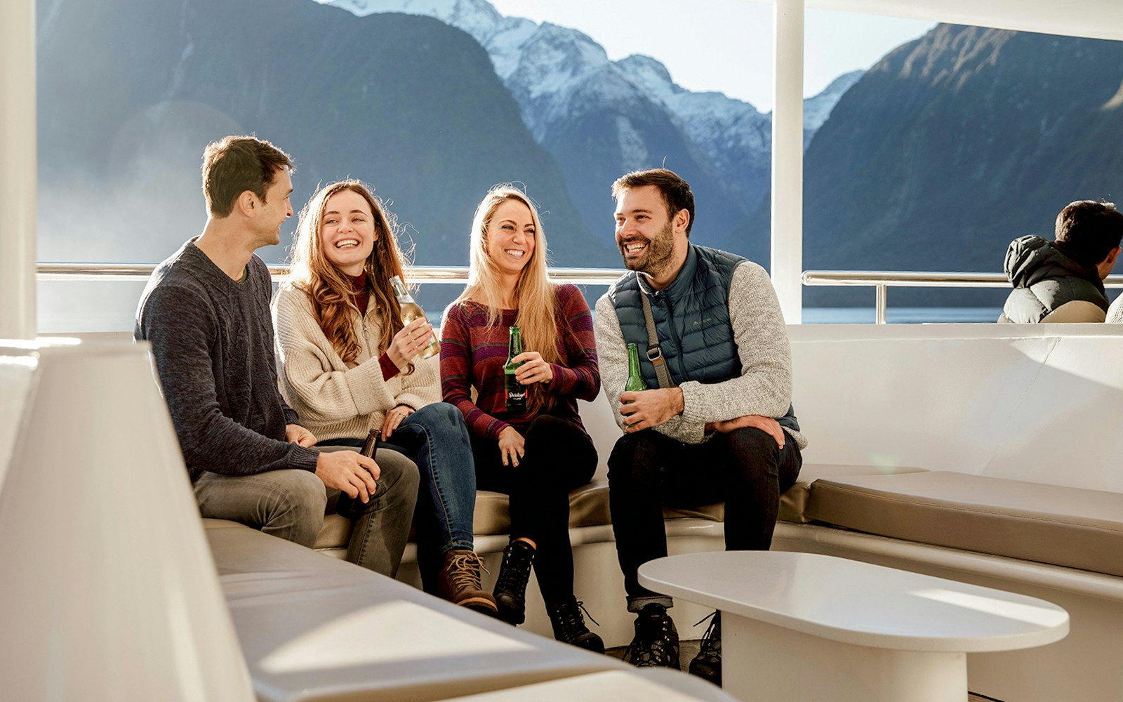 Group enjoying Milford Sound cruise with mountain views, part of Queenstown day trip.