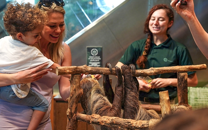 Family interacting with a sloth at Green Planet Dubai.