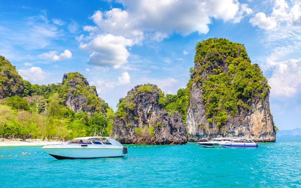 Tourists kayaking through clear waters surrounded by limestone cliffs at Hong Island, Thailand.