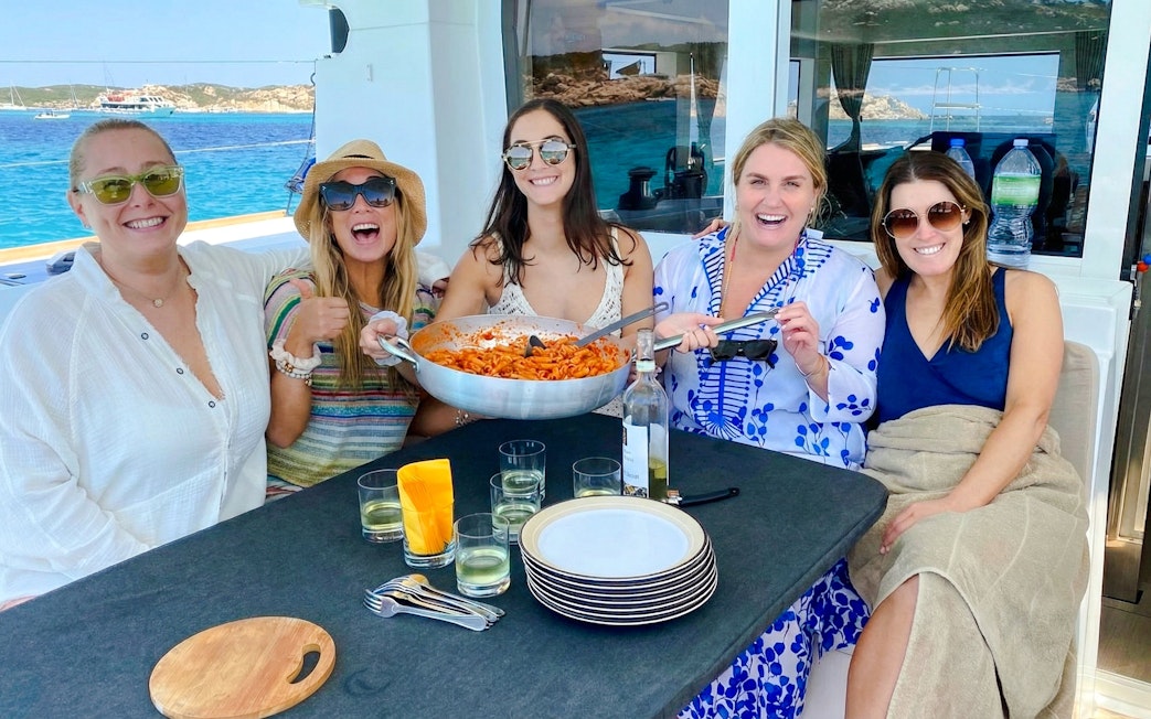 Group enjoying pasta on a catamaran tour in La Maddalena Archipelago.