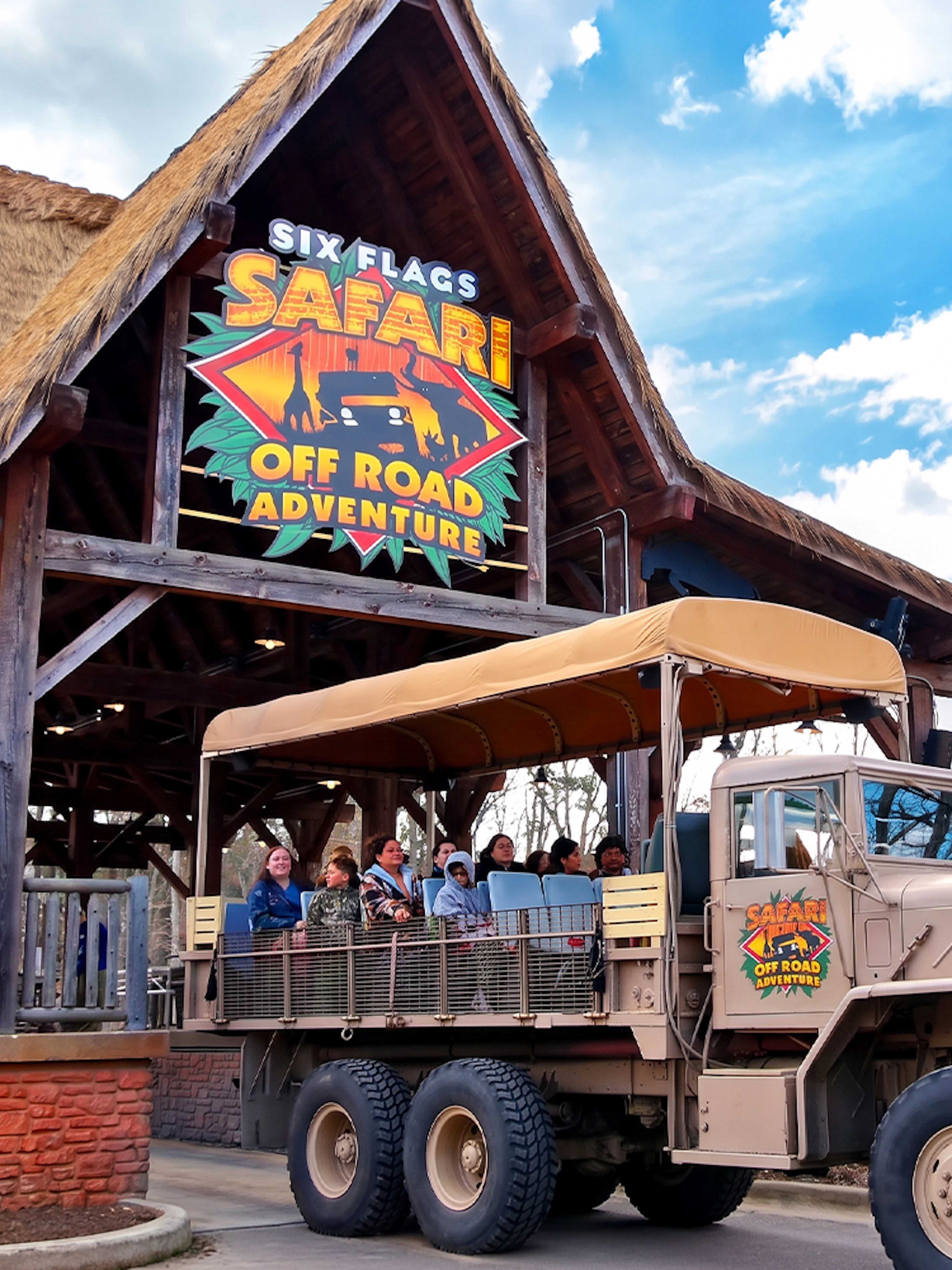Six Flags Wild Safari entrance with off-road adventure truck and passengers.