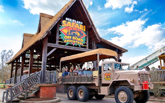 Six Flags Wild Safari entrance with off-road adventure truck and passengers.