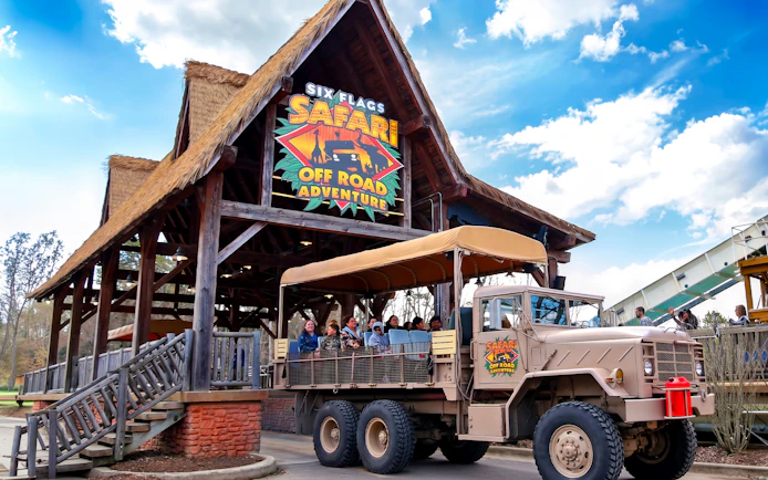 Six Flags Wild Safari entrance with off-road adventure truck and passengers.
