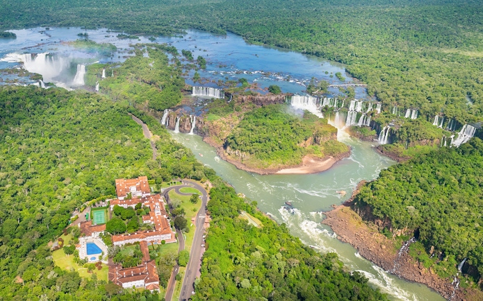 Panoramic view of Iguazu Falls with lush greenery and river, Argentina-Brazil border.