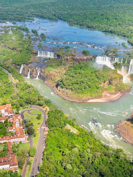 Panoramic view of Iguazu Falls with lush greenery and river, Argentina-Brazil border.
