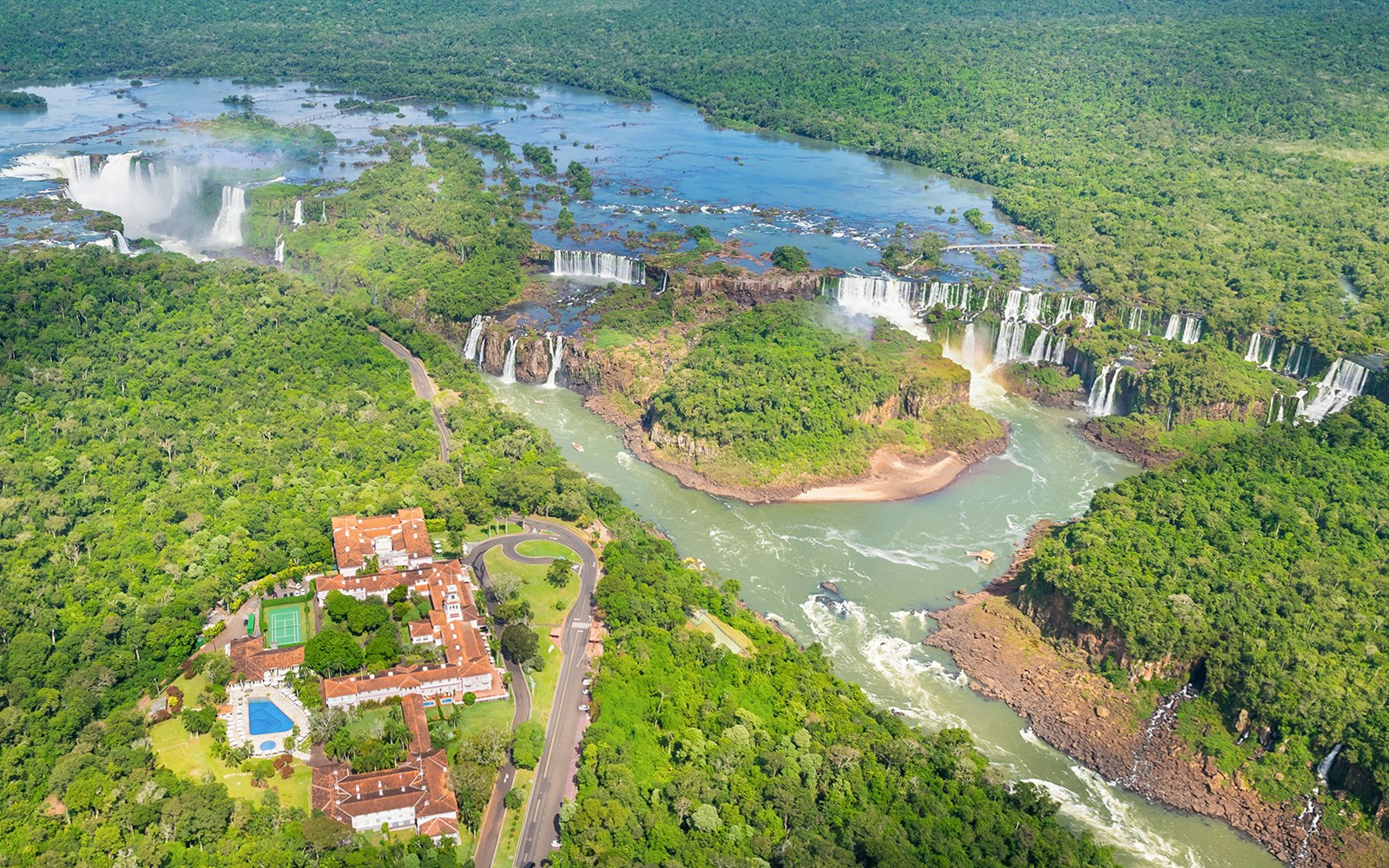 Panoramic view of Iguazu Falls with lush greenery and river, Argentina-Brazil border.