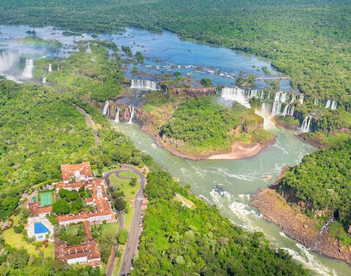 Helicopter view of Iguazu Falls, Argentina, showcasing cascading waterfalls and lush rainforest.