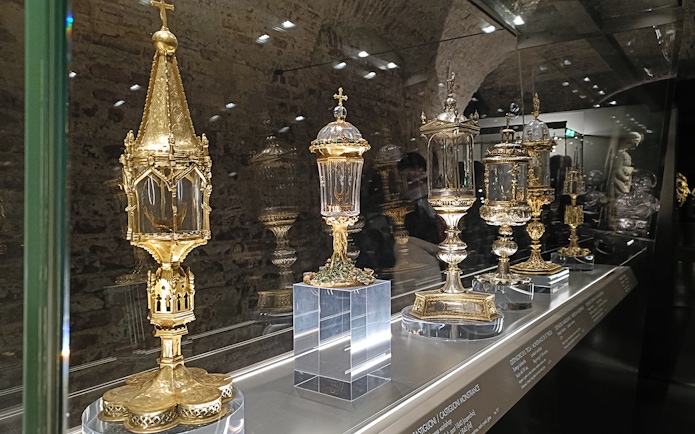 Golden religious artifacts displayed at Duomo Milan Museum exhibit.