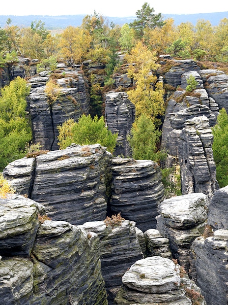 Sandstone rock formations at Tisa Walls Labyrinth with trees and distant hills.