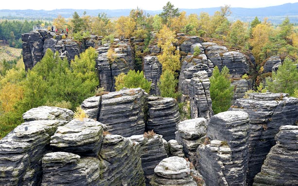 Sandstone rock formations at Tisa Walls Labyrinth with trees and distant hills.