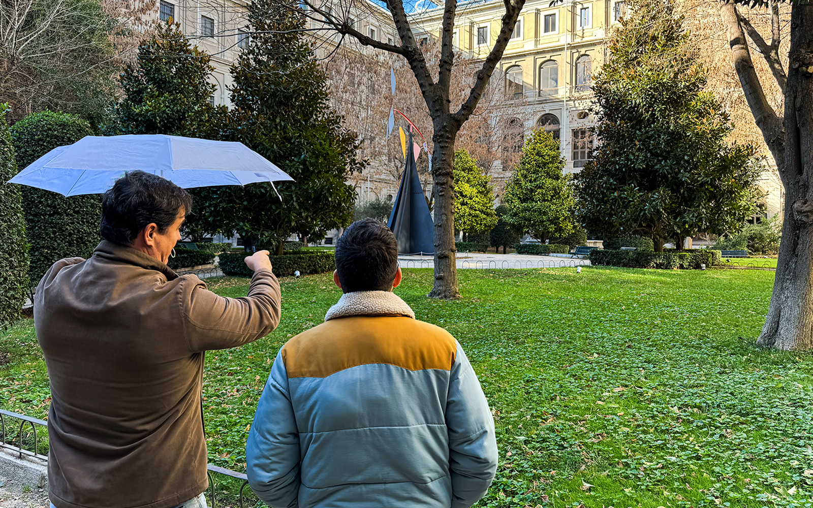 Tour guide pointing at sculpture in garden outside Prado Museum, Madrid.