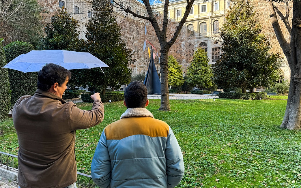 Tour guide pointing at sculpture in garden outside Prado Museum, Madrid.