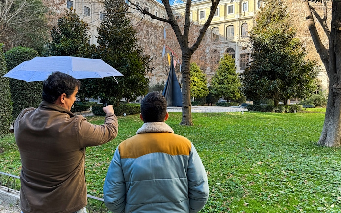 Tour guide pointing at sculpture in garden outside Prado Museum, Madrid.