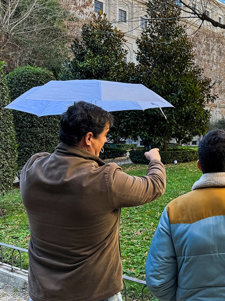 Tour guide pointing at sculpture in garden outside Prado Museum, Madrid.