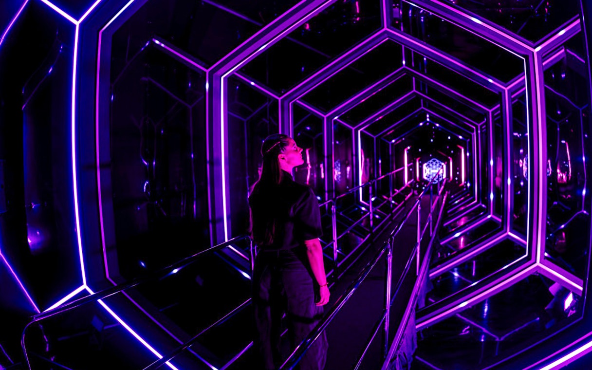 Guest exploring neon-lit tunnel at Amaze Amsterdam.
