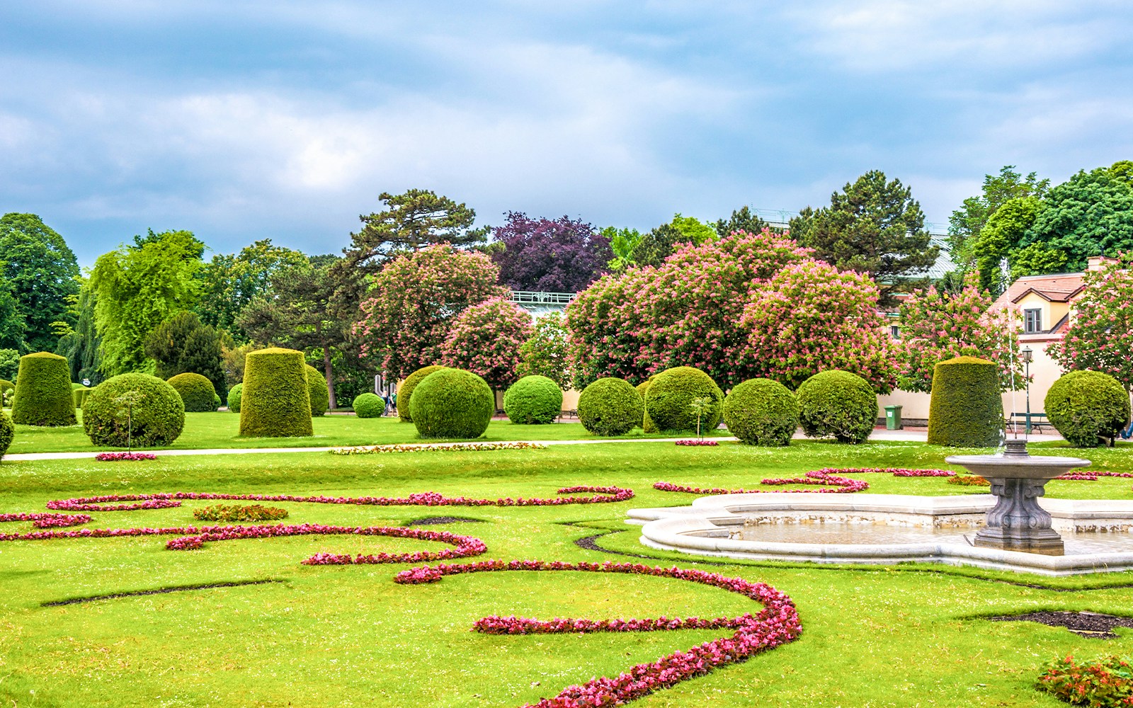 Schönbrunn Palace gardens with manicured hedges and a decorative fountain in Vienna.