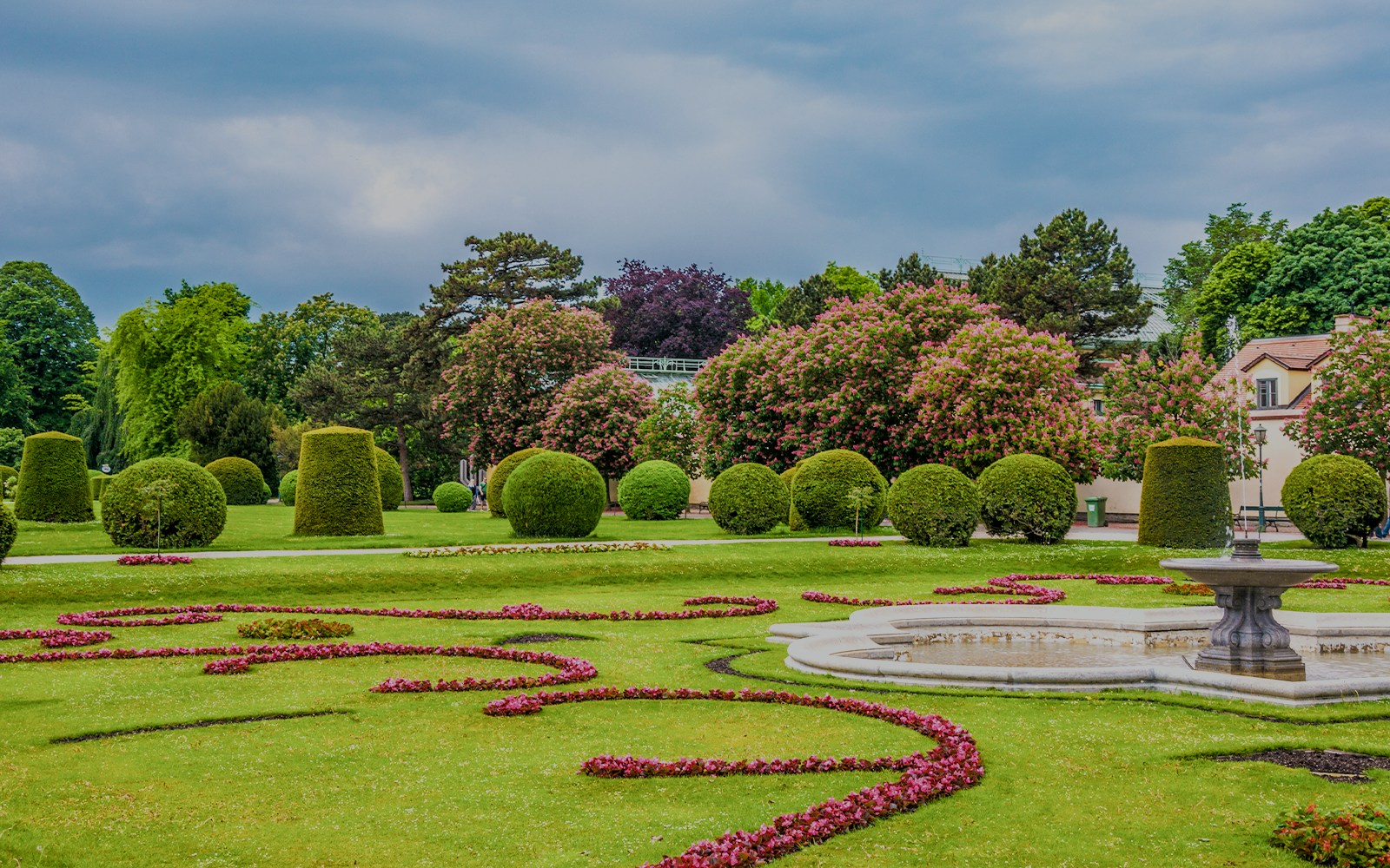 Schönbrunn Palace gardens with manicured hedges and a decorative fountain in Vienna.