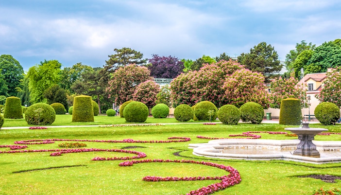 Schönbrunn Palace gardens with manicured hedges and a decorative fountain in Vienna.