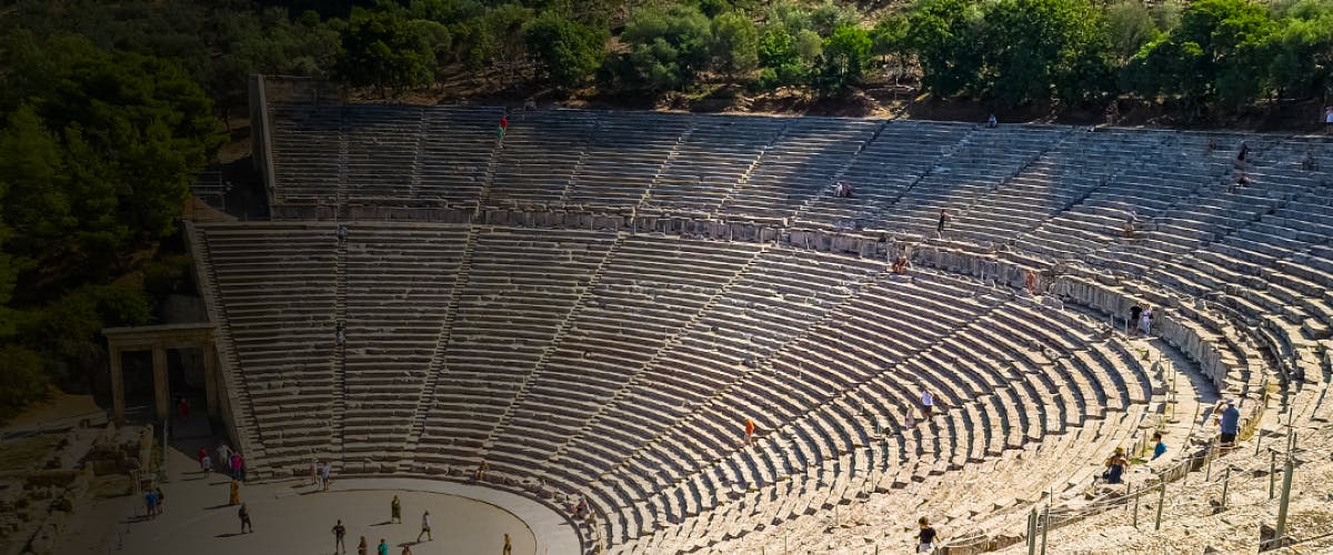 Ancient theater of Epidaurus in Peloponnese, Greece, with visitors exploring the stone seating.