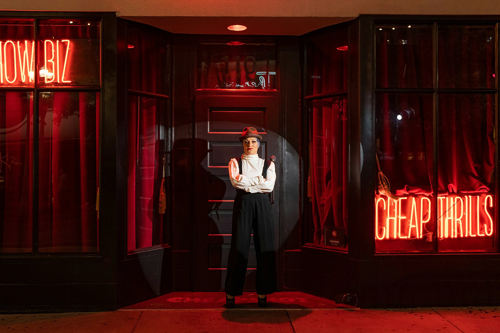 Performer in front of neon signs for Miss Behaves: Maverick's Variety Show.