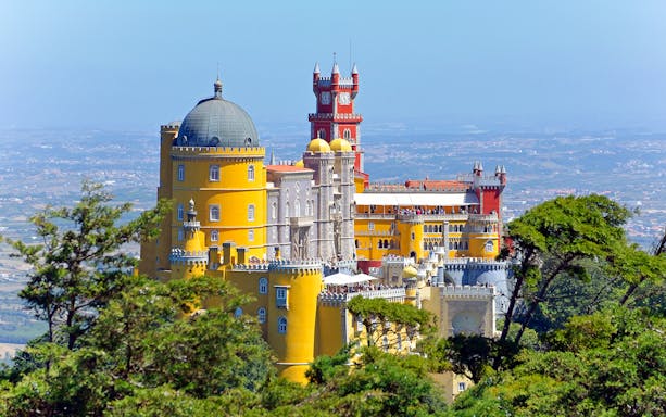 Pena Palace in Sintra, Portugal, with colorful towers and lush greenery.