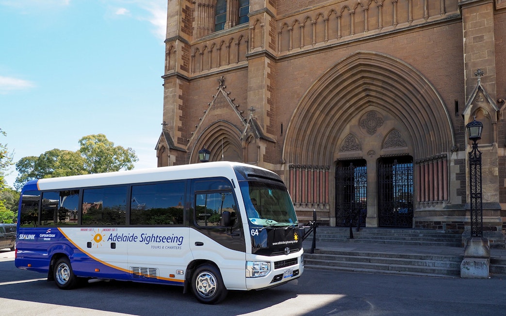 Adelaide sightseeing bus in front of historic cathedral entrance.