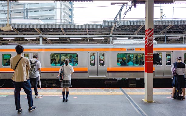 People waiting on a platform for a train at a Japanese station.