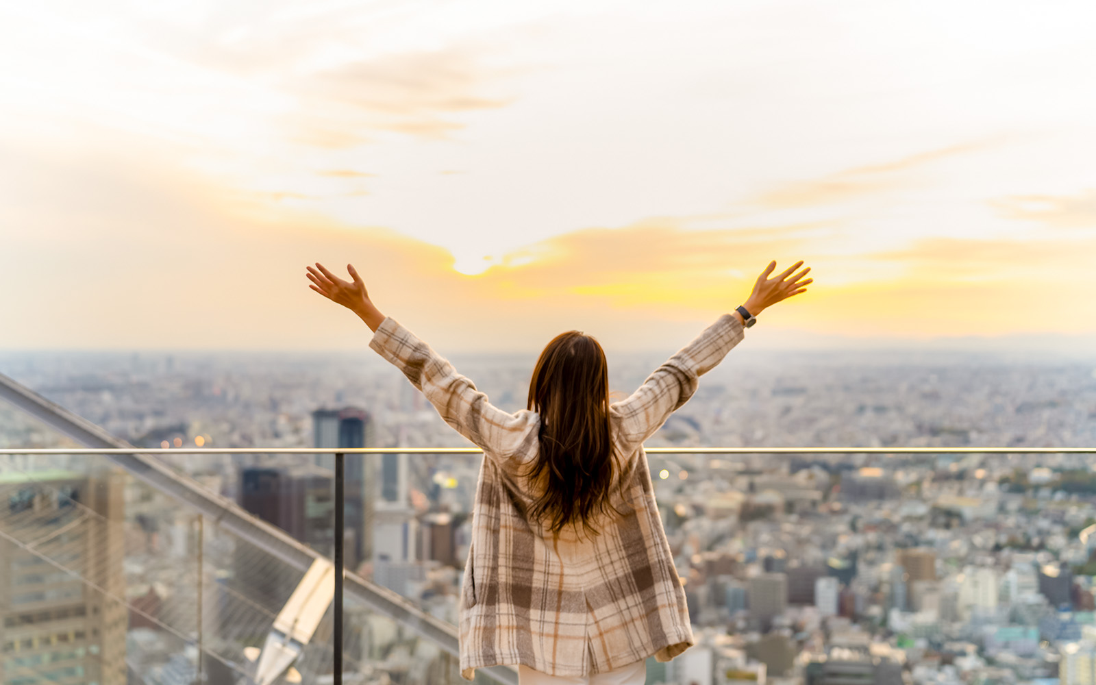 Tourist enjoying sunset view from Shibuya Sky Deck in Tokyo.