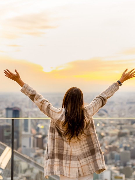 Tourist enjoying sunset view from Shibuya Sky Deck in Tokyo.
