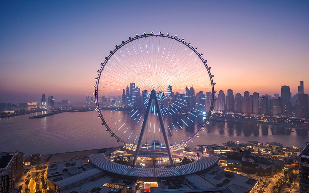 Ain Dubai Ferris wheel with city skyline at sunset.