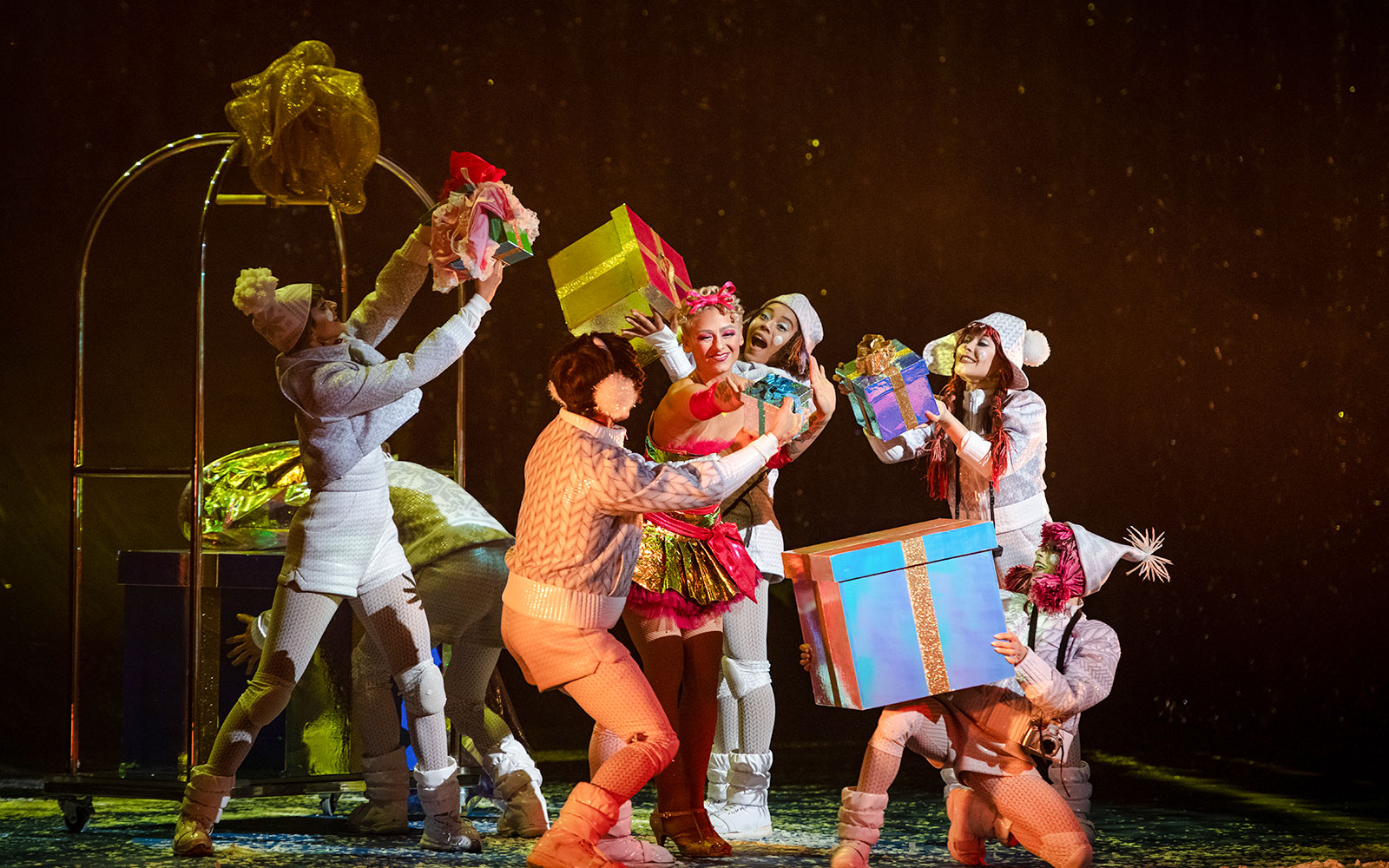 Performers in festive costumes holding gifts during Cirque du Soleil 'Twas The Night Before show.
