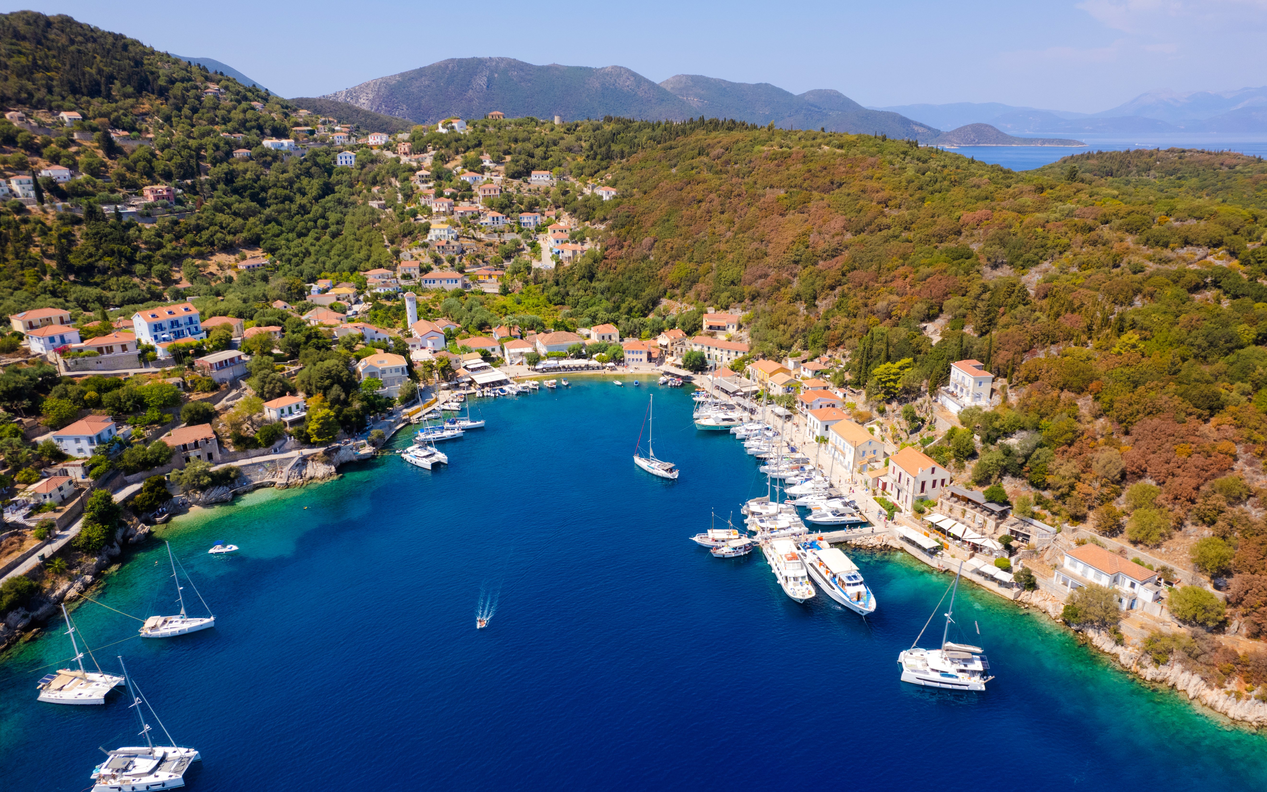 Aerial view of Kioni village harbor with boats and hillside homes, Ithaca, Greece.