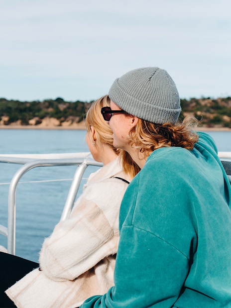 Couple enjoying Cape Woolamai coastline view from Phillip Island morning cruise.