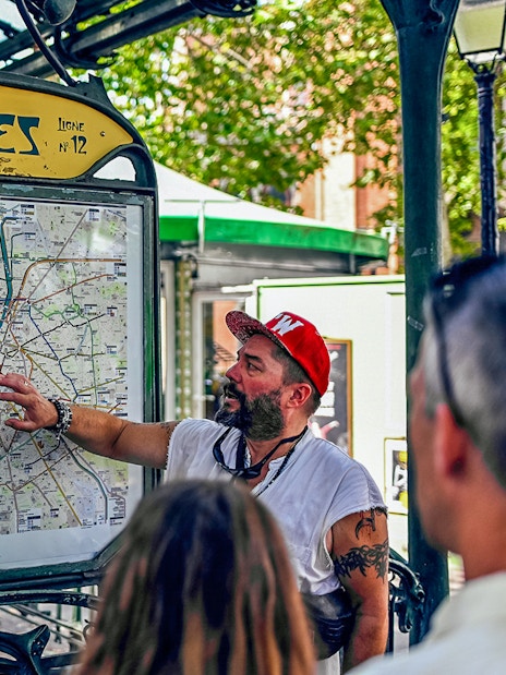 Tour guide explaining Paris map at Abbesses station during Montmartre food tour.