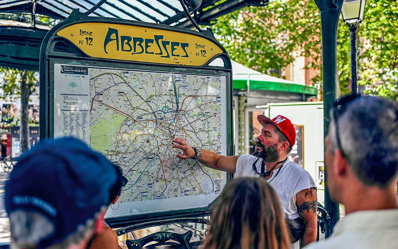 Tour guide explaining Paris map at Abbesses station during Montmartre food tour.