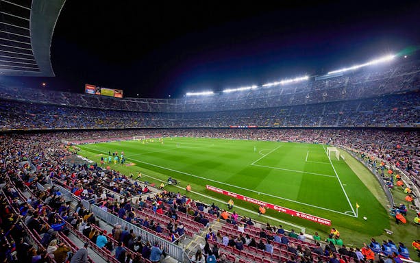 Crowd watching a night football match at FC Barcelona's Camp Nou stadium.