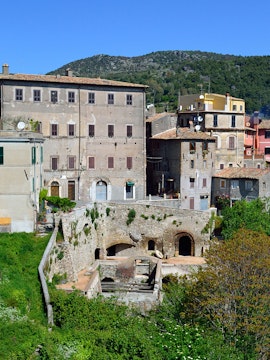 Historic buildings in Tivoli, Italy, with lush greenery and hills in the background.