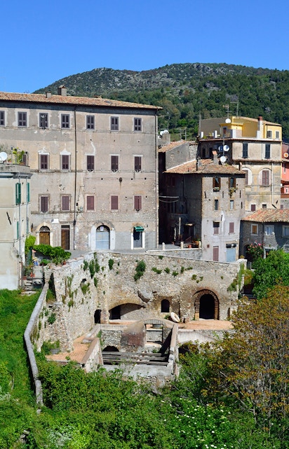 Historic buildings in Tivoli, Italy, with lush greenery and hills in the background.