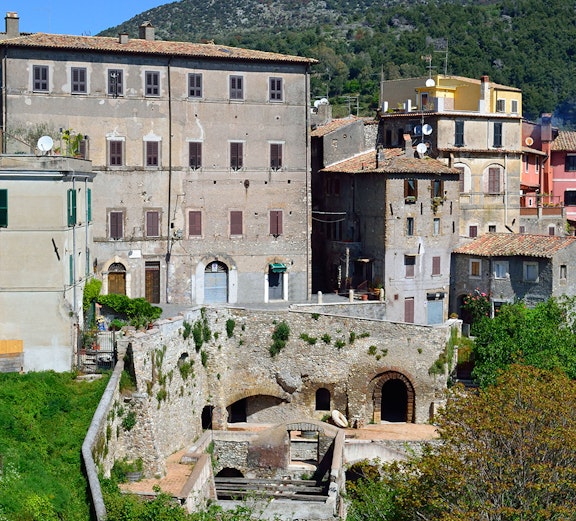 Historic buildings in Tivoli, Italy, with lush greenery and hills in the background.
