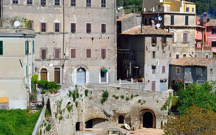 Historic buildings in Tivoli, Italy, with lush greenery and hills in the background.