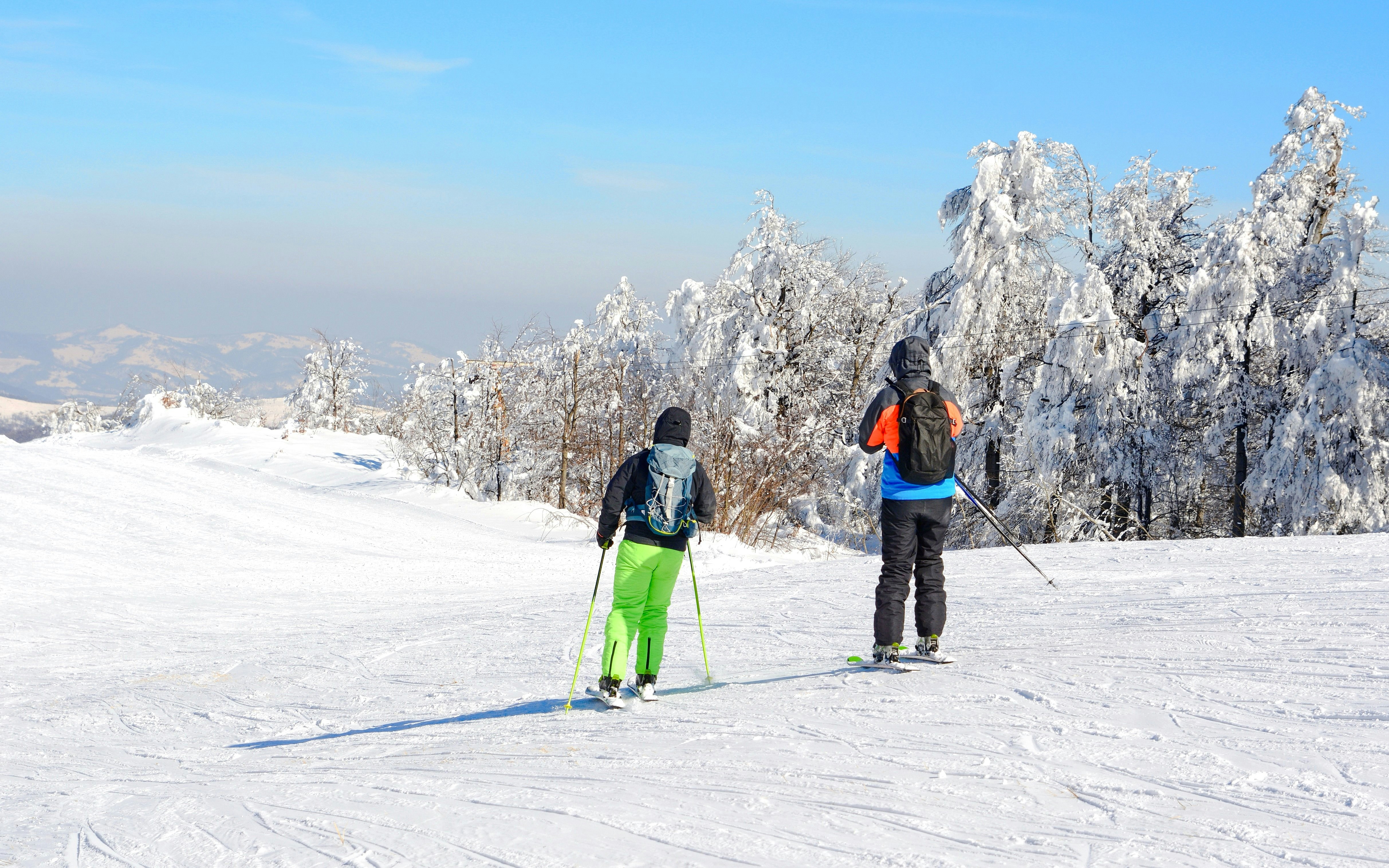 Skiers on a snowy slope surrounded by snow-covered trees at a ski resort.