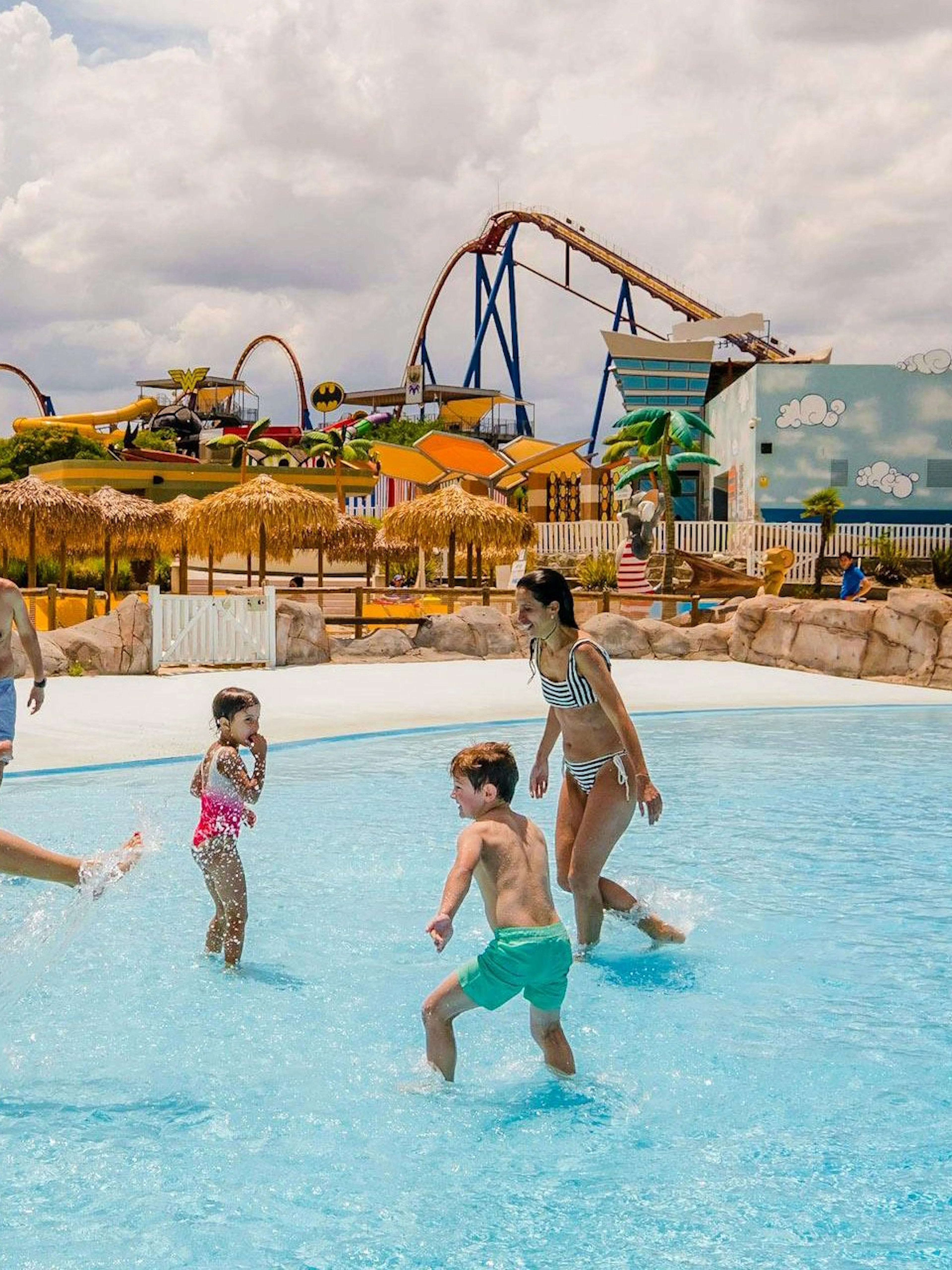 Families enjoying the wave pool at Parque Warner Beach with roller coasters in the background.