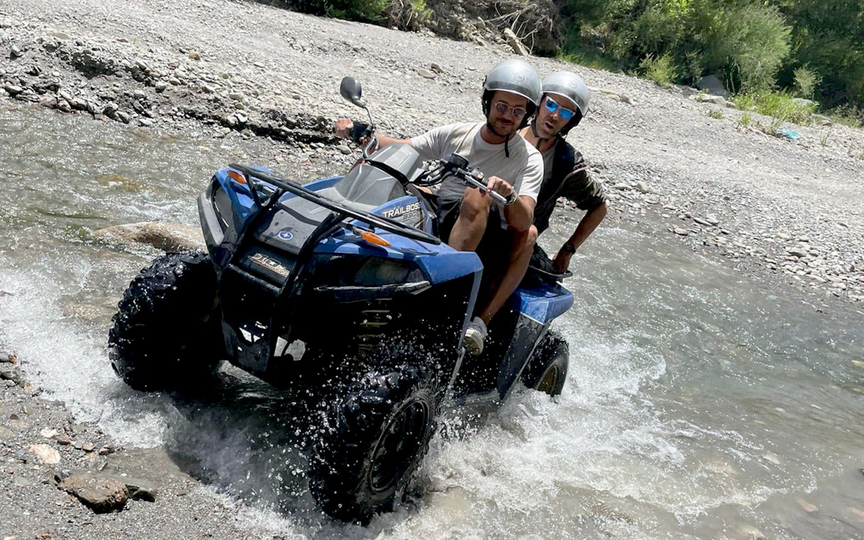 Two people riding a quad bike through a stream in Alcantara Gorges, Sicily.