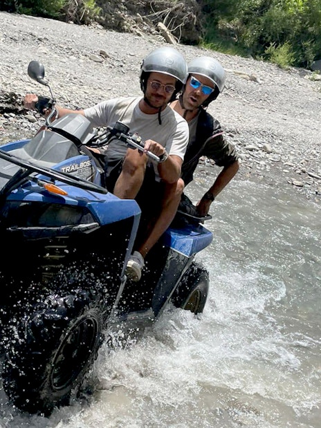Two people riding a quad bike through a stream in Alcantara Gorges, Sicily.