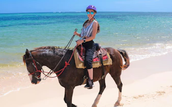 Person horseback riding along Macao Beach with ocean in the background.