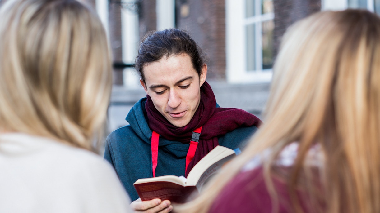 Tour guide reading to visitors on the Anne Frank Walking Tour in Amsterdam.